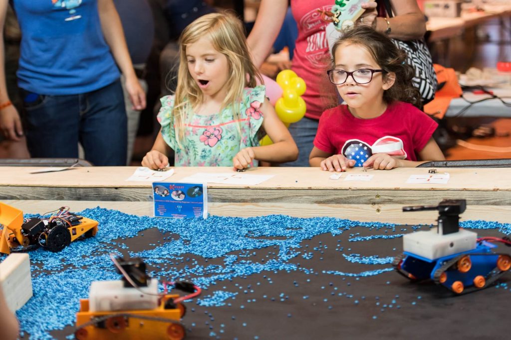 Girls learn STEM driving construction robots made by Kinvert STEM students